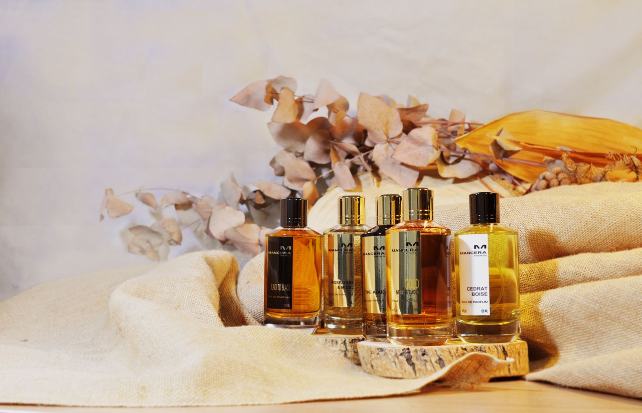 Aesthetic display of luxury perfume bottles with natural dried botanicals and linen backdrop.