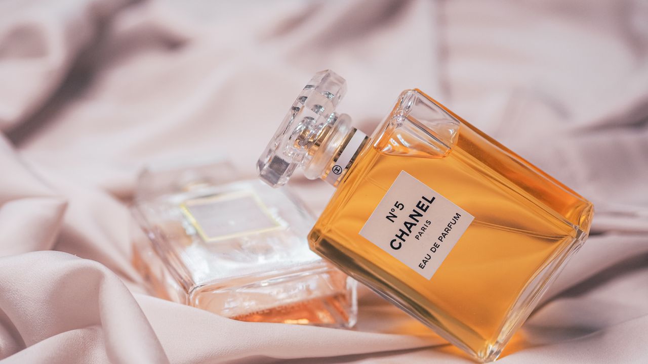 Close-up of Chanel No. 5 perfume bottles elegantly placed on soft pink fabric.